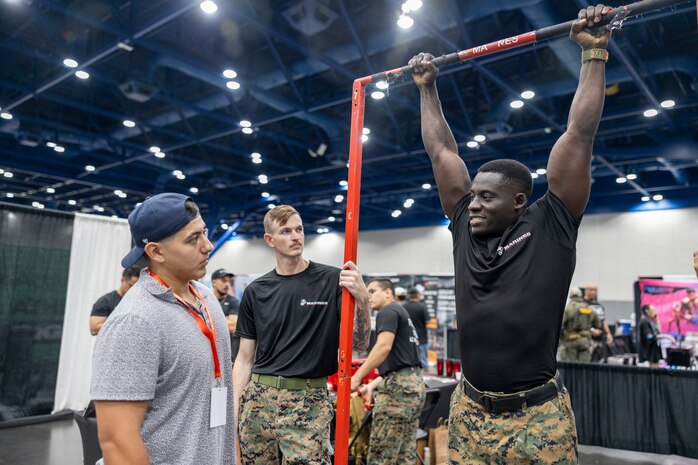 U.S. Marine Corps Sgt. Kofi Boateng, Jr., right, a recruiter with Recruiting Sub Station Memorial City, Recruiting Station Houston, demonstrates how to execute a pull-up for an attendee during the American Fitness Expo at the George R. Brown Convention Center in Houston, Texas, Aug. 3, 2024. Marines with RS Houston held a recruiting booth alongside fitness influencers, health vendors; and professional athletes to challenge attendees and vendors alike in a pull-up bar challenge. (U.S. Marine Corps photo by Sgt. Ryan H. Pulliam)