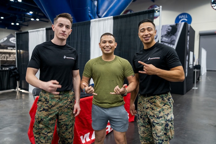 U.S. Marine Corps Sgt. Cory Budvarsontigue, left, an operations clerk with Recruiting Station Houston, 8th Marine Corps District, and Staff Sgt. Luis Hernandez, a recruiter with Recruiting Sub Station Deer Park, RS Houston, pose for a photo with an attendee during the American Fitness Expo at the George R. Brown Convention Center in Houston, Texas, Aug. 3, 2024. Marines with RS Houston held a recruiting booth alongside fitness influencers, health vendors; and professional athletes to challenge attendees and vendors alike in a pull-up bar challenge. (U.S. Marine Corps photo by Sgt. Ryan H. Pulliam)