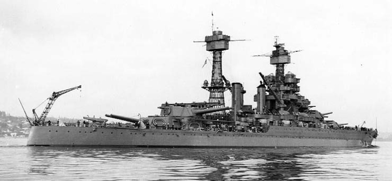 A battleship floats in a harbor.