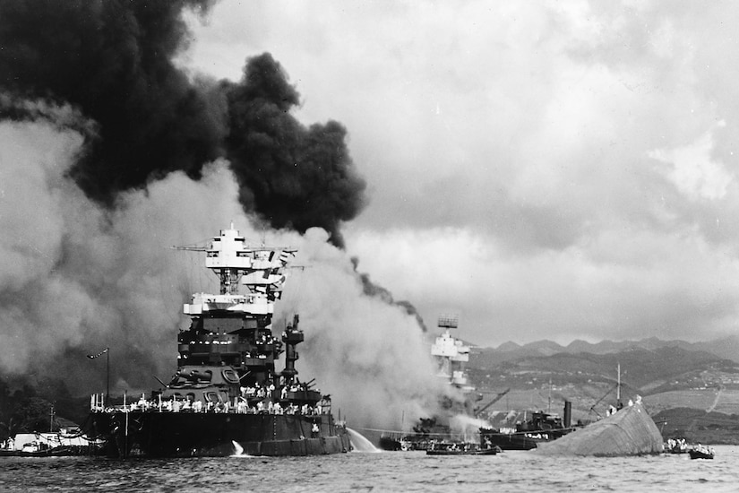 Battleships in a harbor sustain damage as smoke billows.