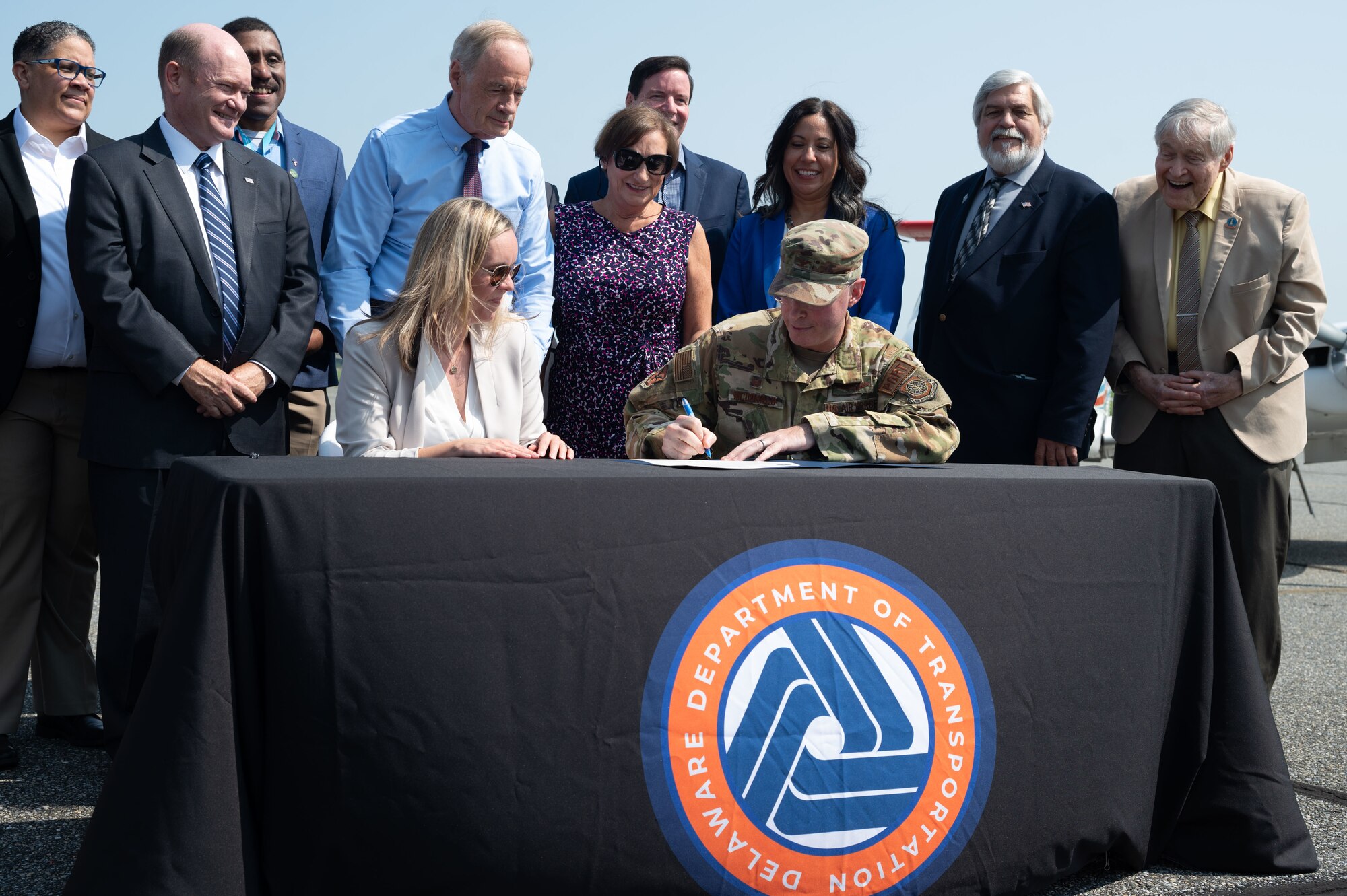 Leaders from around the state of Delaware look on as U.S. Air Force Col. Chris McDonald, 436th Airlift Wing commander, signs the Joint Use Agreement at Dover, Delaware, Aug. 15, 2024. This agreement allows the use of Dover AFB's flying facilities by the Delaware Department of Transportation for approved civilian and commercial flights. (U.S. Air Force photo by Senior Airman Dieondiere Jefferies)