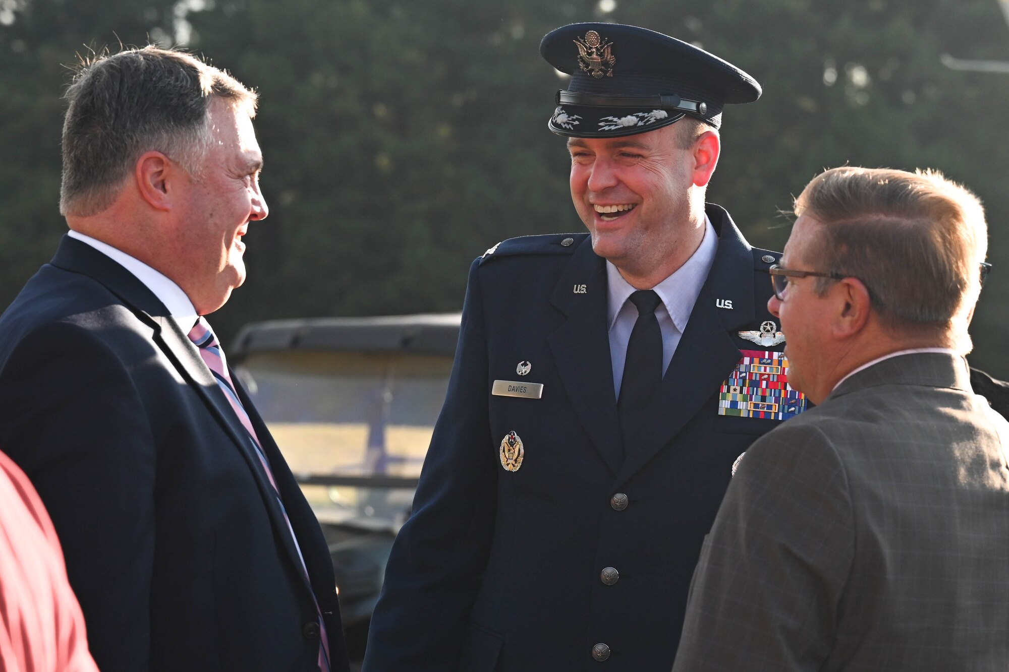A man in uniform smiles and greets other people at a ceremony.
