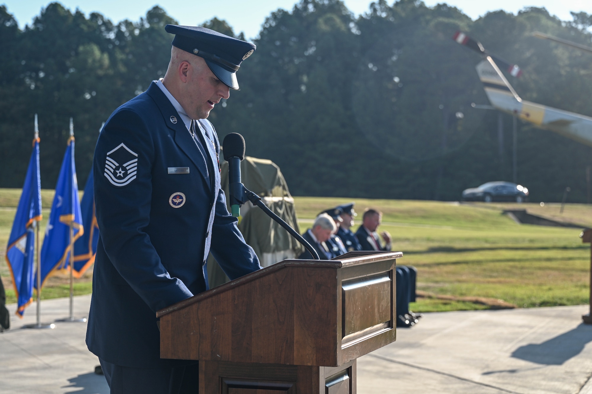A man in uniform looks down at a podium while addressing a crowd.