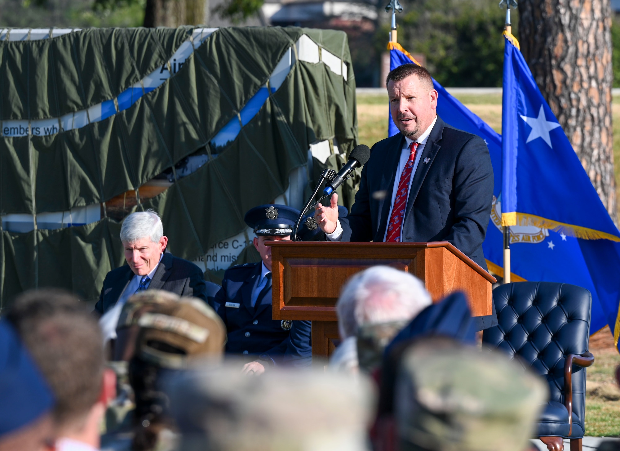 A man stands behind a podium and addresses a crowd.