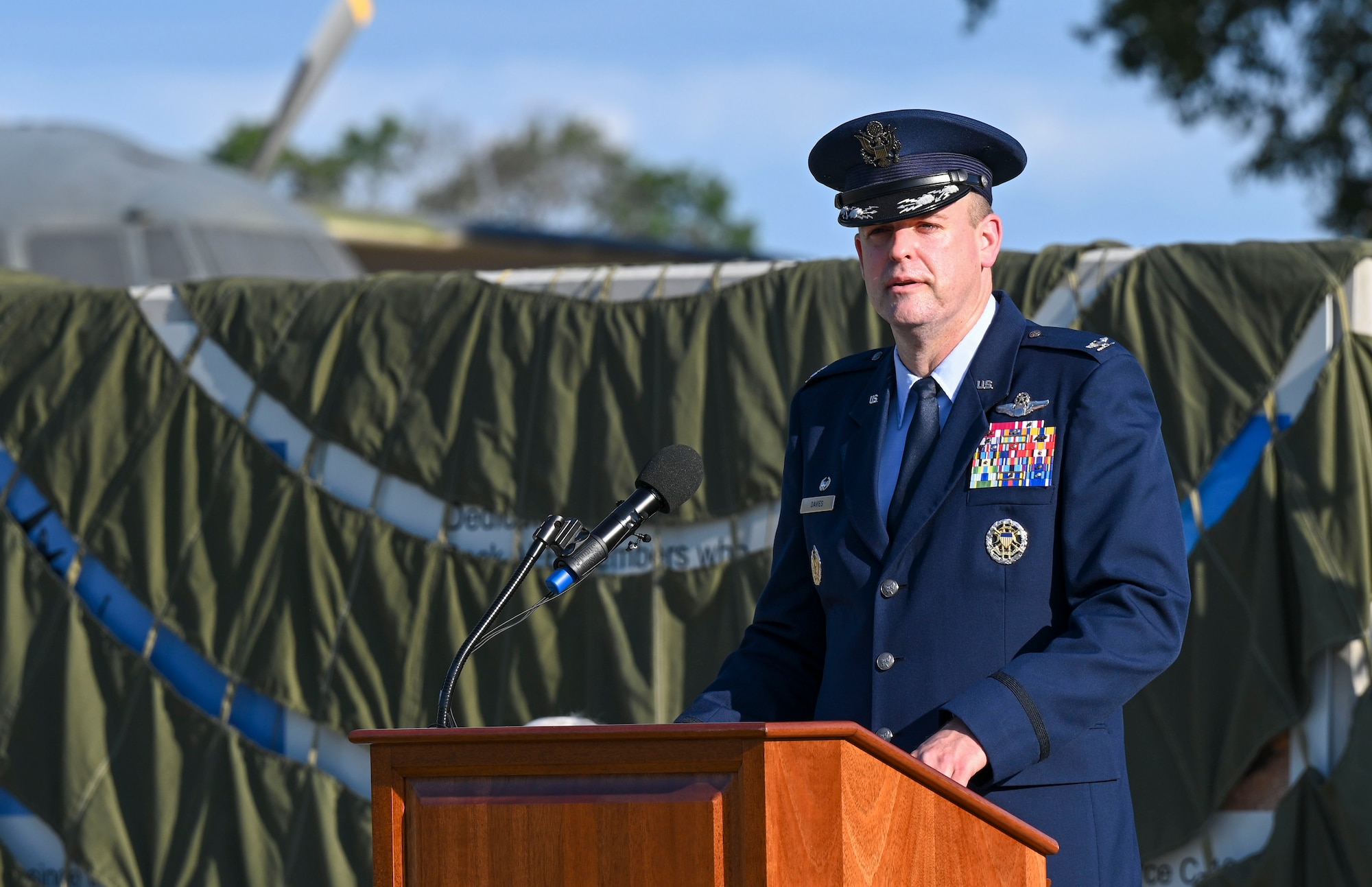 A man in uniform stands behind a podium and addresses a crowd.