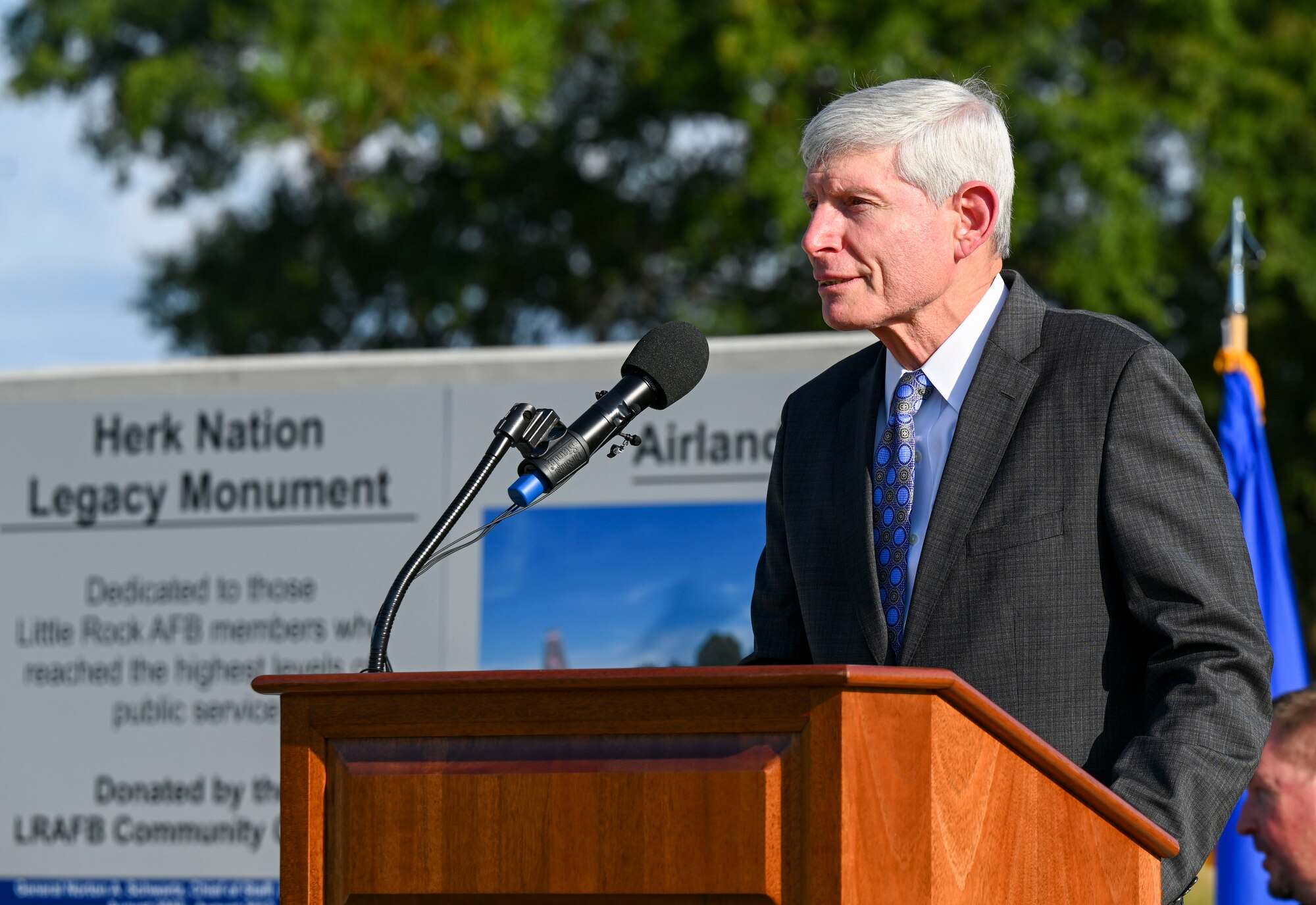 A man behind a podium speaks to a crowd at a dedicaiton ceremony.
