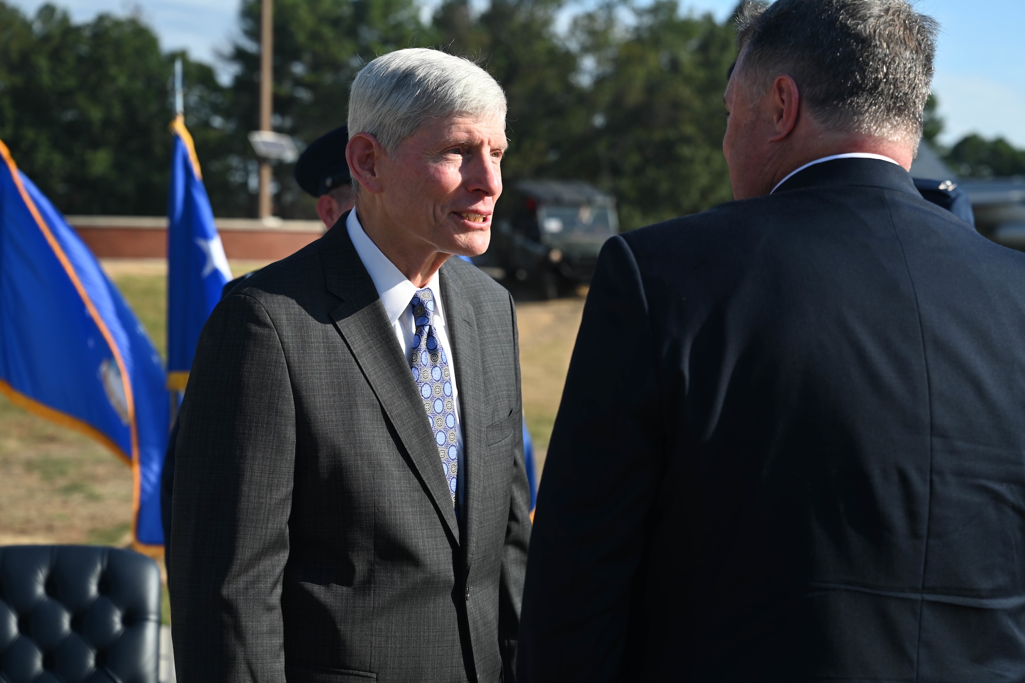 Two men talk at a dedication ceremony for a monument.