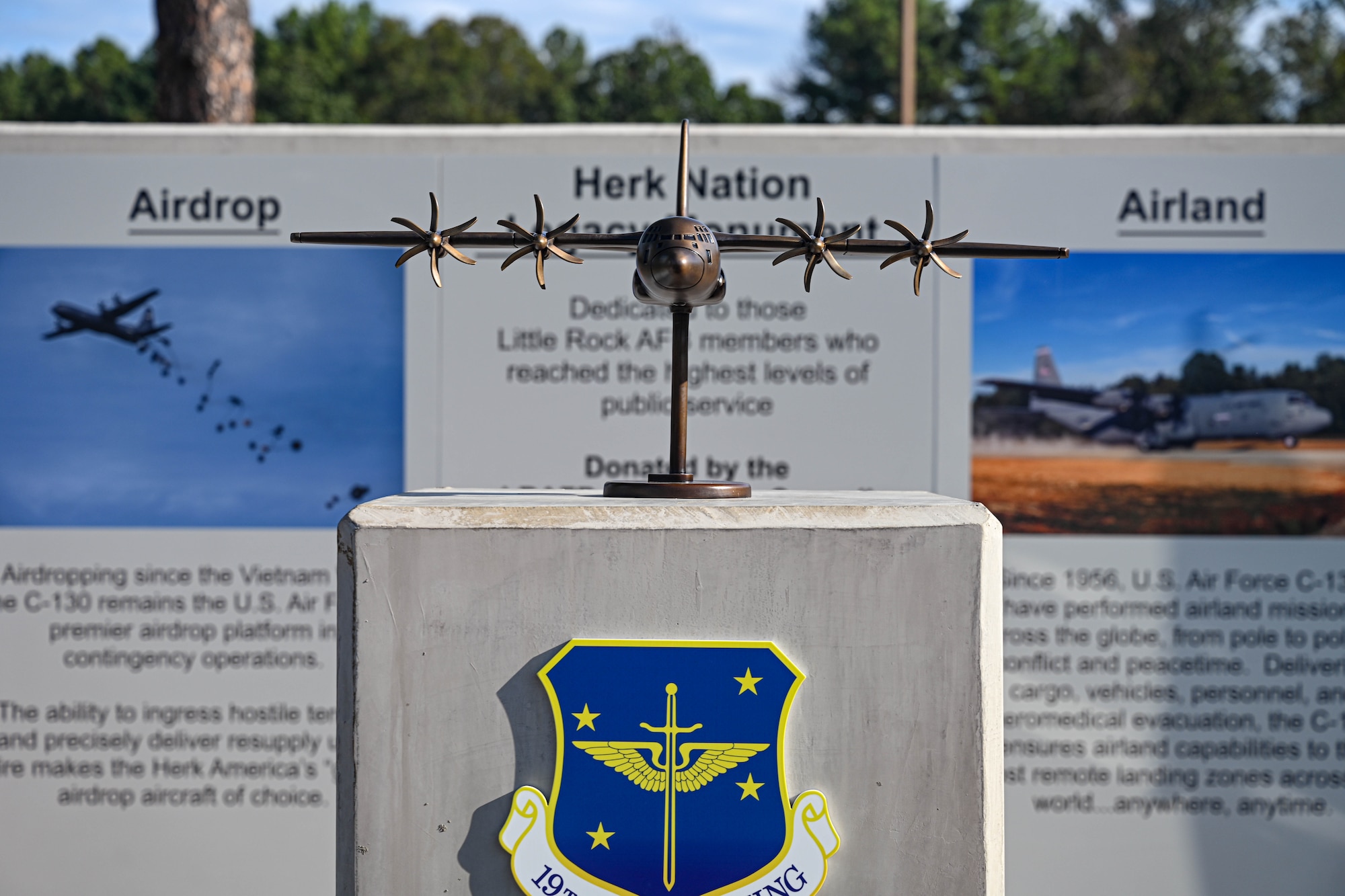 A bronze C-130J Super Hercules aircraft model unveiled as part of the Herk Nation Legacy Monument, stands on a podium.