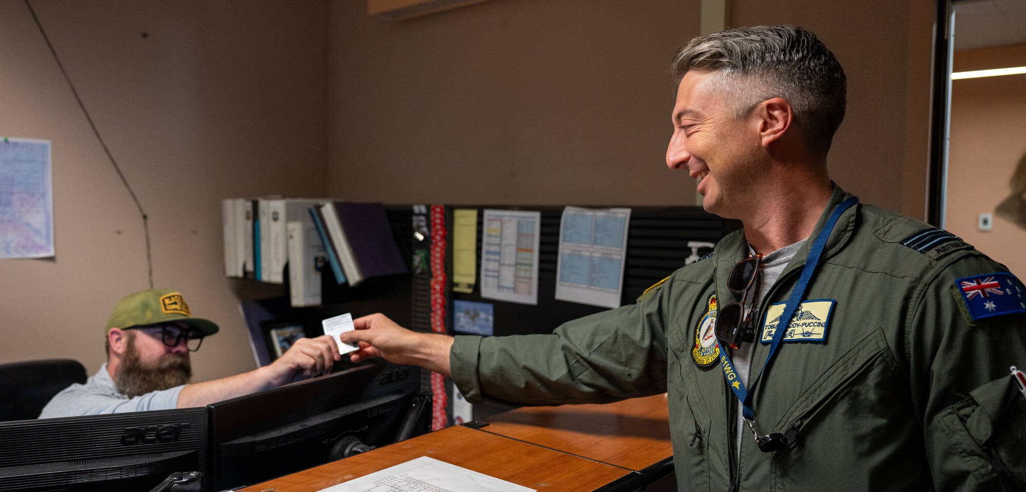 Royal Australian Air Force Squadron Leader Tobias Liddy-Puccini, 81 Wing Weapons staff officer, hands his badge to a member of the 353rd Combat Training Squadron to check in for the exercise.