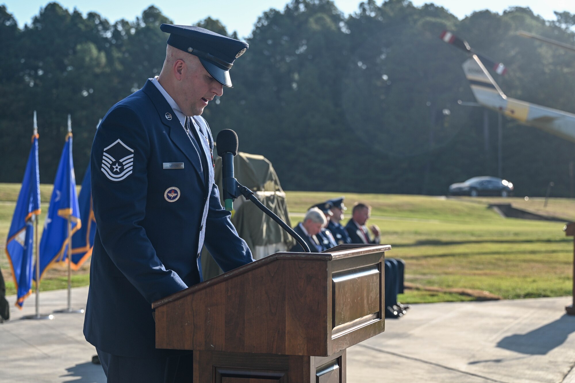A man in uniform looks down at a podium while addressing a crowd.