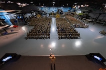 Man in uniform on stage speaking out to a crowd.