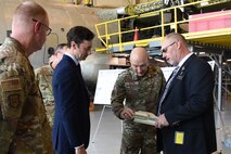 Group of men looking at small airplane part