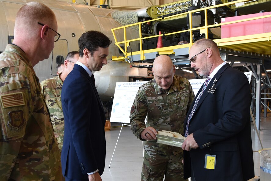Group of men looking at small airplane part