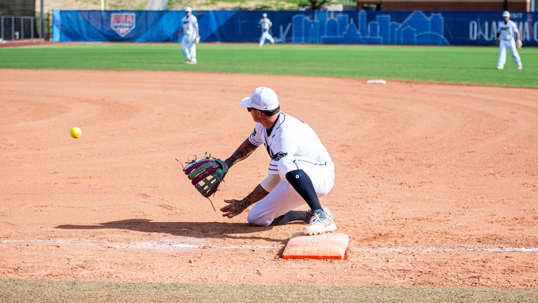 U.S. Navy Chief Petty Officer Nick Ludwig, a member of team Navy, attempts to catch a ball thrown to first base during a game at Devon Park in Oklahoma City, on Aug. 15, 2024. The 2024 Armed Forces Men’s and Women’s Softball Championship hosted by USA Softball at the USA Softball National Hall of Fame Complex from 13-19 August features Service members from the Army, Marine Corps, Navy, Air Force (with Space Force personnel) and Coast Guard.  Teams will battle it out for gold. (U.S. Air Force photo by Staff Sergeant James Crow)