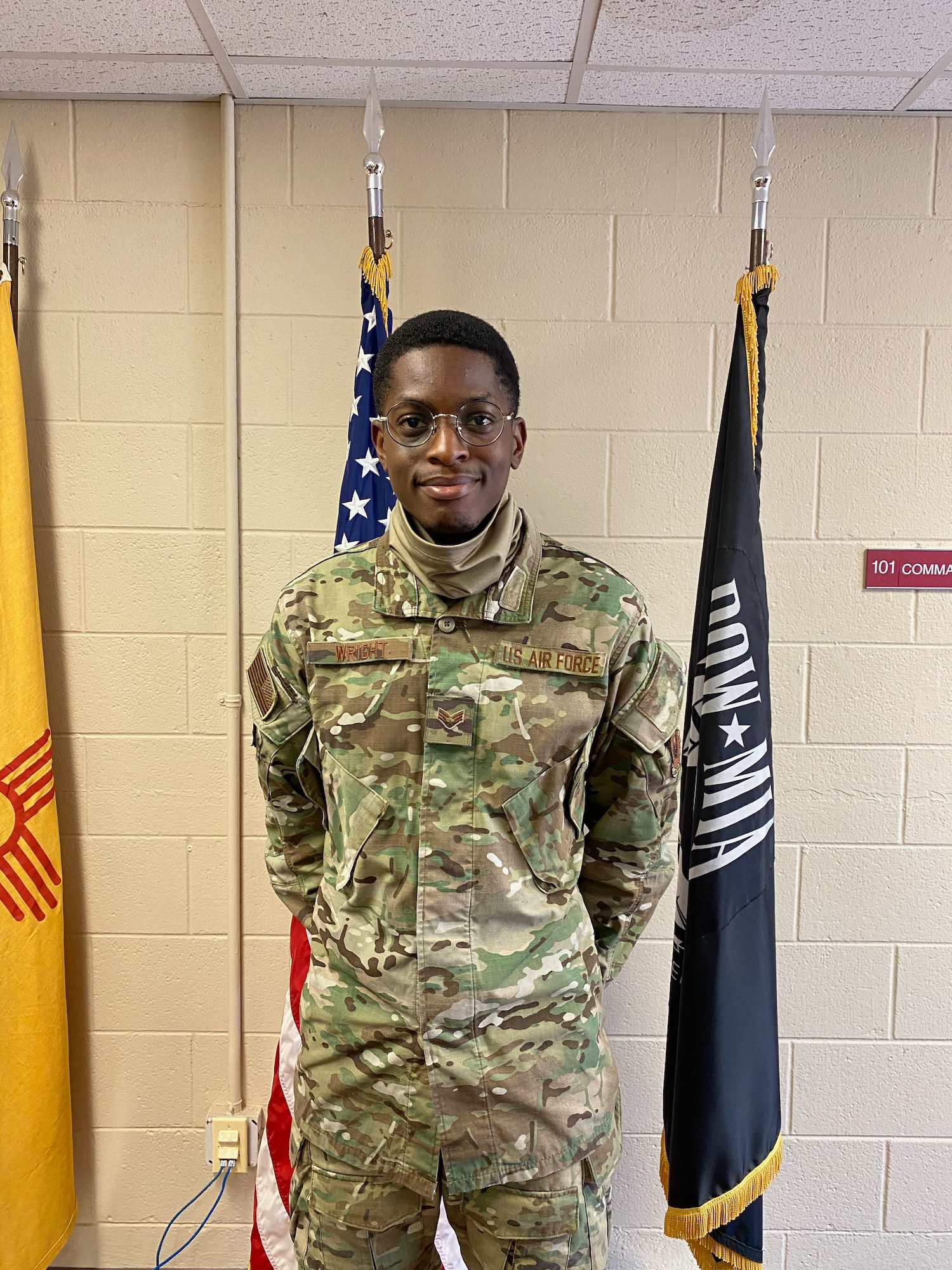 A man stands in military uniform in front of two flags.