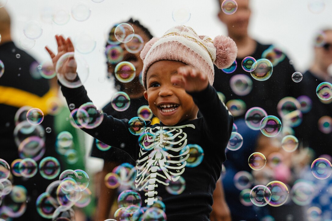 A smiling child plays in bubbles during an Army community event.