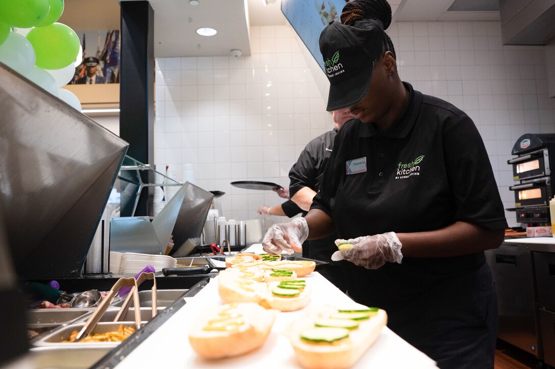 Women prepares sub sandwiches in a kitchen.