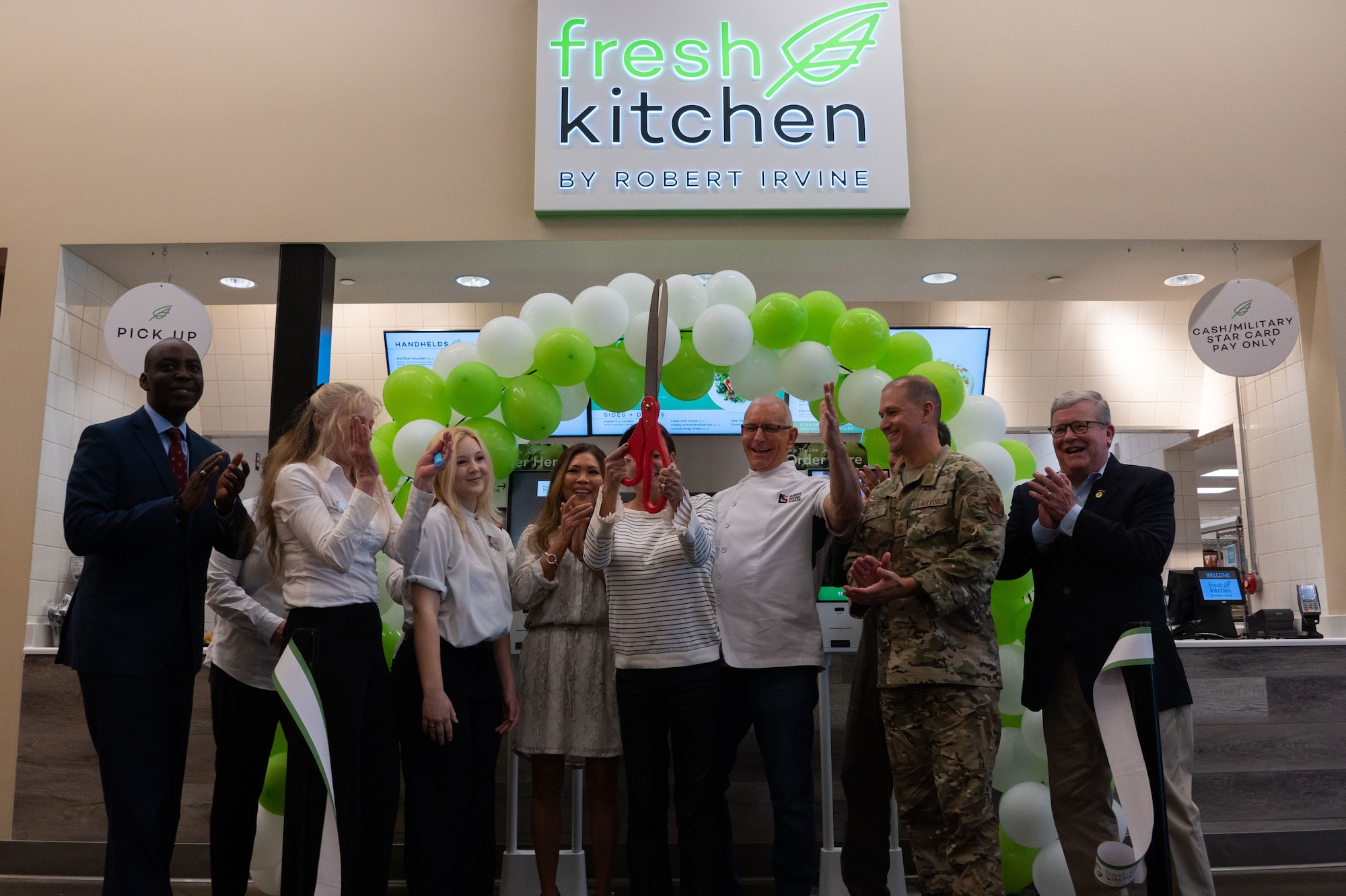 A group of people celebrating and clapping after cutting a ribbon.