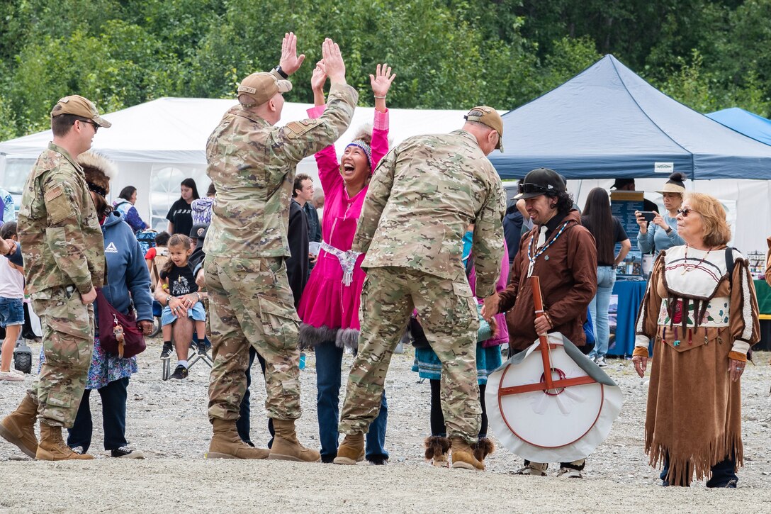 Service members greet residents standing in a line during a ceremony.