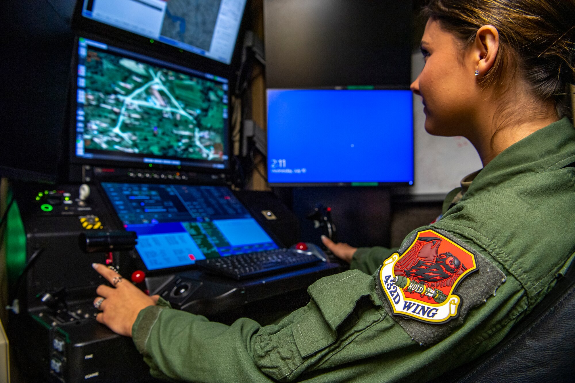 A woman in a flight suit operates a flight simuator.