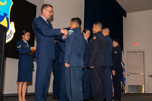 Col. Bryan Tuinman, commandant of the Inter-American Air Forces Academy, pins an international military student during IAAFA’s graduation at Joint Base San Antonio-Lackland Texas, Aug. 7, 2024.