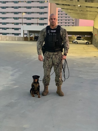 Master-at-Arms 2nd Class Jordan Morales stands next to Military Working Dog Orca at Naval Base San Diego, California, on December 12, 2019.