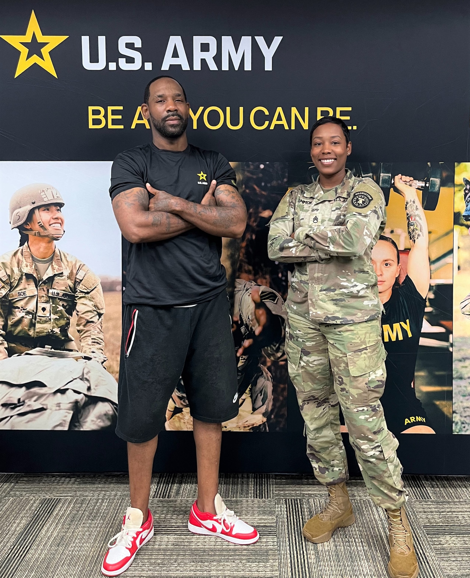 Man and female soldier stand in front of a banner with photos and U.S. Army logo.
