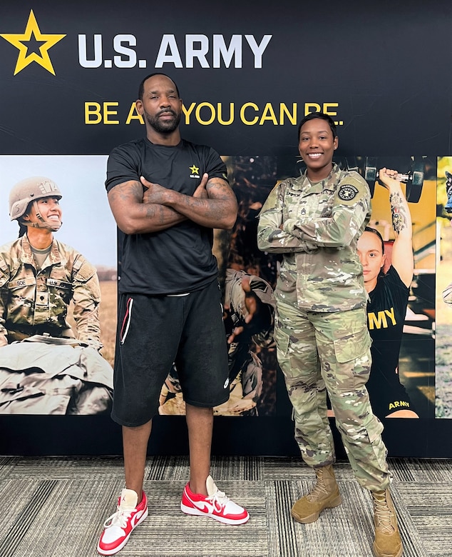 Man and female soldier stand in front of a banner with photos and U.S. Army logo.