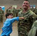 1st Sgt. Anthony Womack’s 12-year-old son, Hunter Krimminger, firmly affixes his father’s new rank to his chest.
