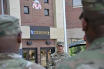 U.S. Army Soldier framed in the photograph by two other U.S. Army Soldiers, all in uniform, stand outside the Future Soldier Preparatory Course school house