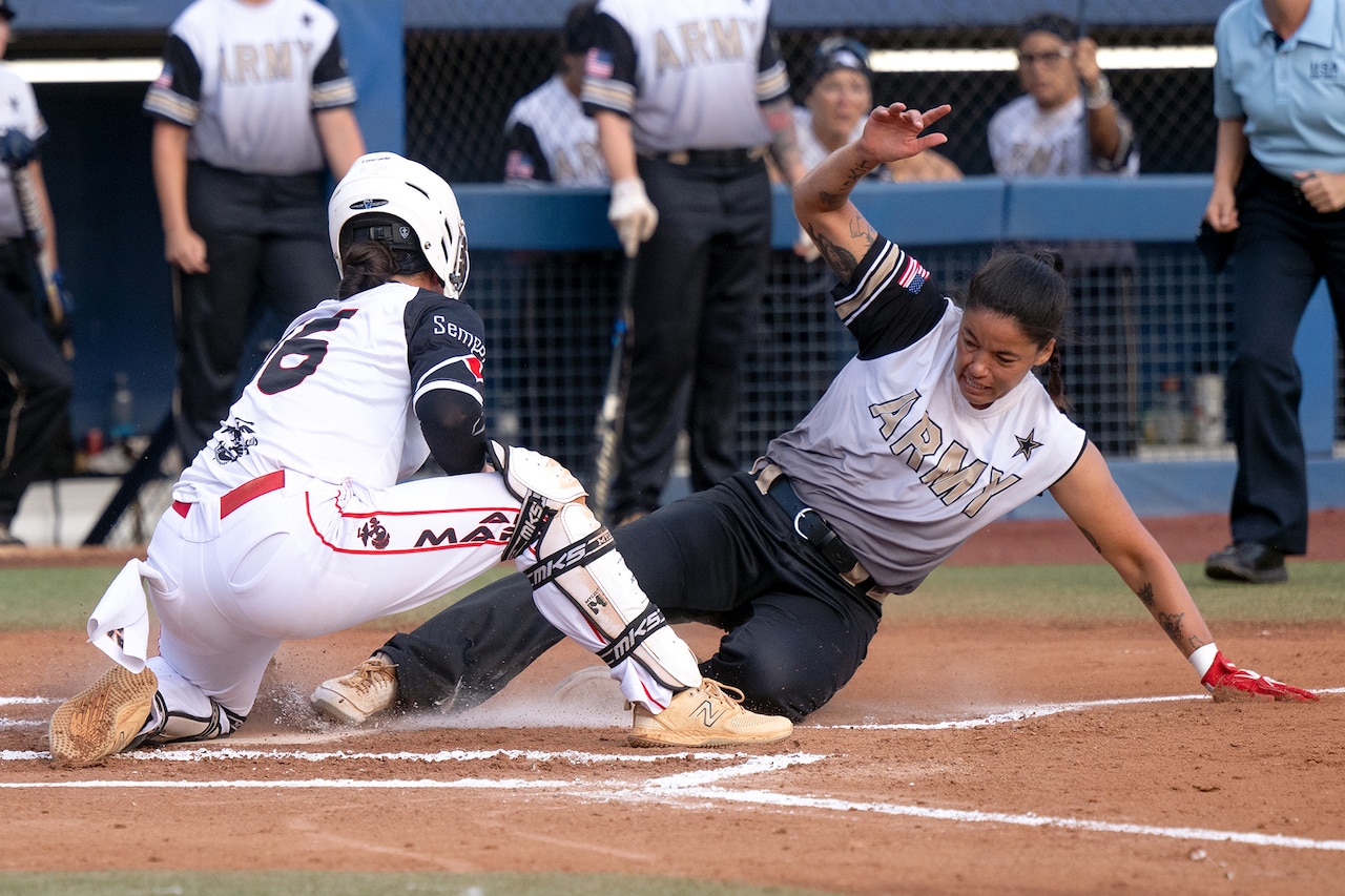 A softball player slides into home plate while another player applies a tag.
