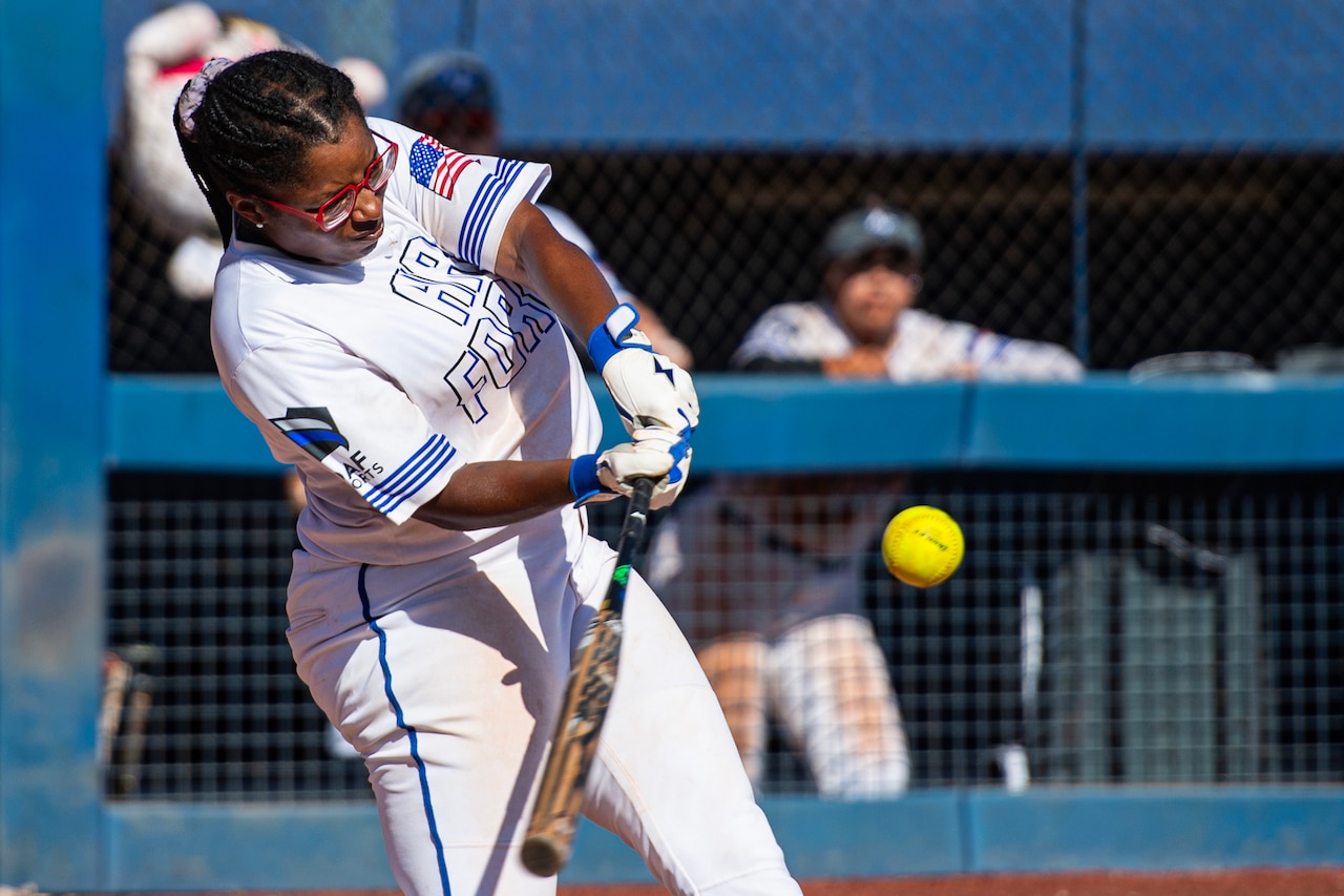 A softball player hits a ball.