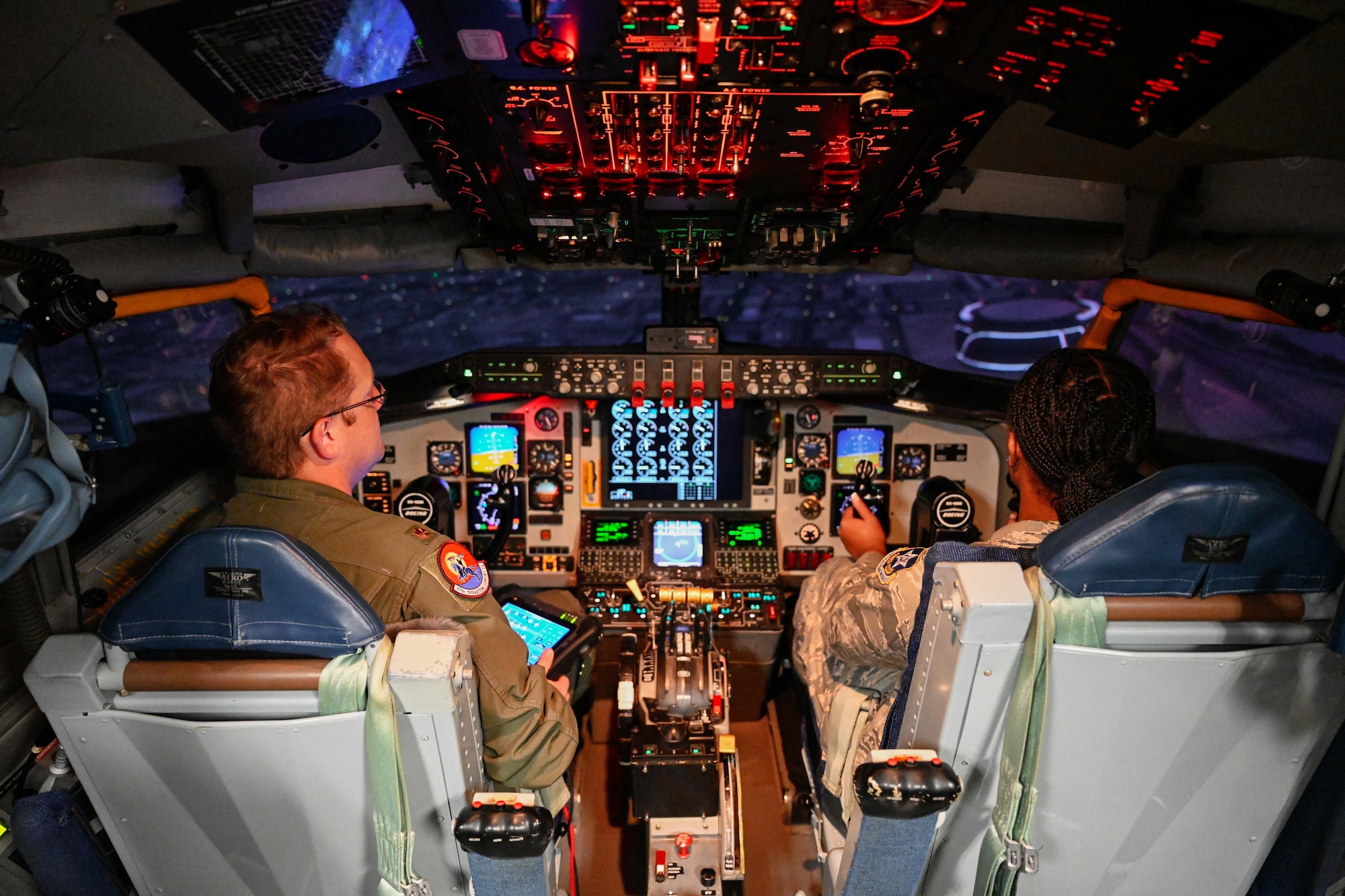 U.S. Air Force Maj. Barry James, 97th Operations Support Squadron director of staff, and Trianna Winkfield, Altus Chapter Civil Air Patrol cadet, fly a KC-135 Stratotanker aircraft in a flight simulator at Altus Air Force Base, Oklahoma, Aug. 12, 2024. All of the cadets were able to attempt to land the simulator, exposing them to what the pilots go through each time they fly. (U.S. Air Force photo by Airman 1st Class Jonah Bliss)