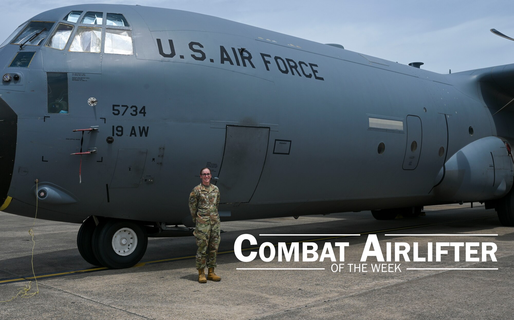 A woman in uniform stands outside in front of a C-130J Super Hercules aircraft.