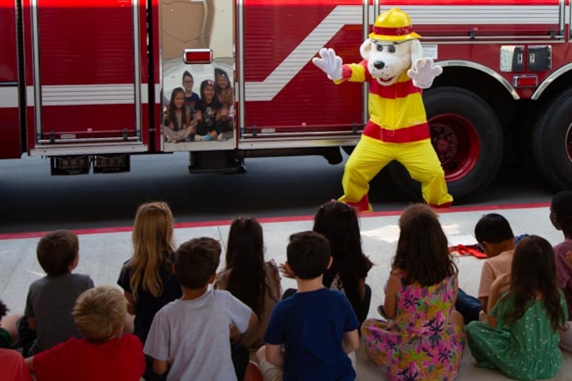 Children sit near a firetruck.