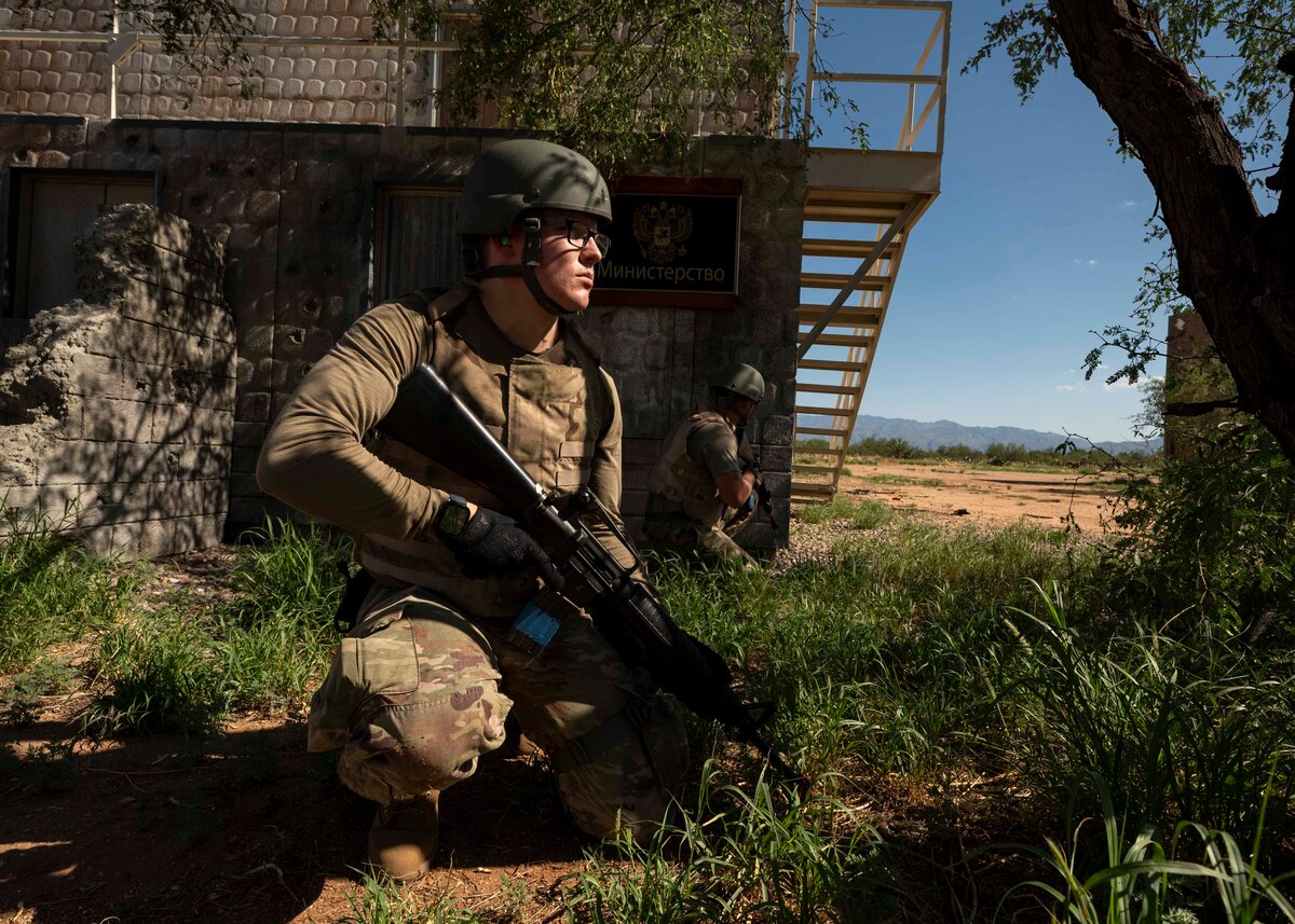 People in military uniforms crouch with rifles.