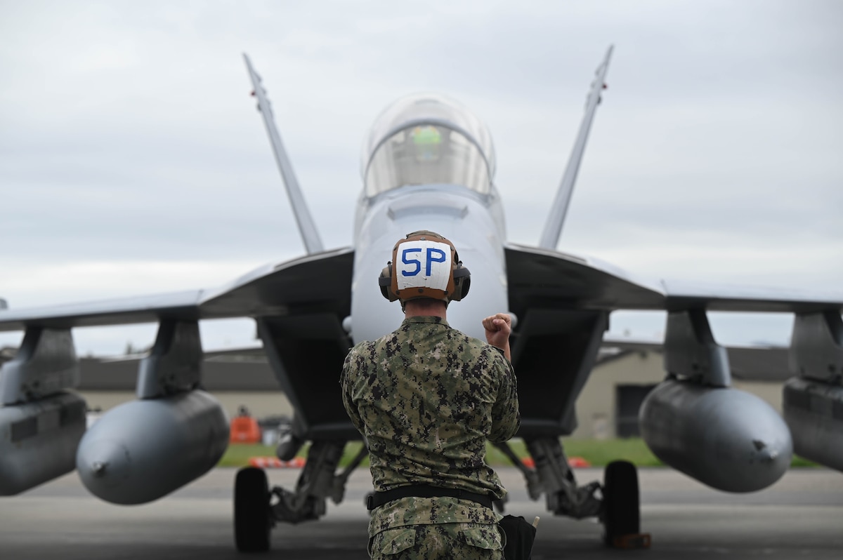 U.S. Navy Seaman Ayden Nuttbrock, Electronic Attack Squadron (VAQ-135) aviation machinist mate, guides an E/A-18G Growler through pre-flight checks during Red Flag-Alaska 24-3 at Eielson Air Force Base, Alaska, Aug. 19, 2024.