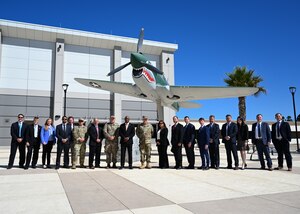 People pose together for a group photo in front of a plane display.