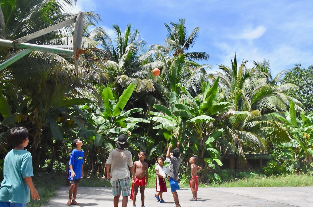 The crew of the USCGC Oliver Henry (WPC 1140) play basketball with residents of Satawal, Federated States of Micronesia, after safely returning six rescued fishermen and their 22-foot fiberglass boat to the community on Aug. 18, 2024. The vessel, which had been adrift after experiencing engine failure, was towed to Satawal Atoll by Oliver Henry, who arrived roughly two hours later. The Joint Rescue Sub-Center (JRSC) Guam watch received a distress alert from a 406MHz Personal Locator Beacon (PLB) registered in the United States at approximately 9 a.m. local time on Aug. 17. The beacon, lent out by a Yap-based owner to outer island fishermen, was activated, signaling potential distress about 27 nautical miles north northeast of Satawal. (U.S. Coast Guard photo by Petty Officer 3rd Class Ryder Nollan)