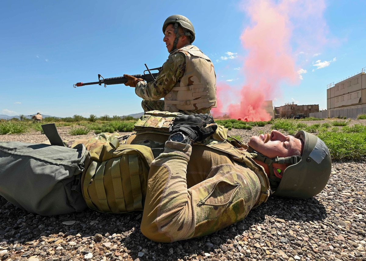 Men in military uniforms sit next to red smoke.