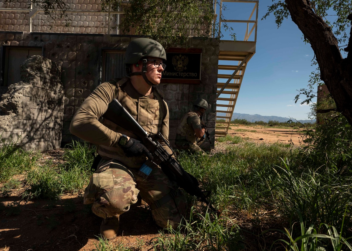 People in military uniforms crouch with rifles.