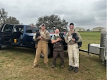 Military Working Dog instructors hold their MWDs: Tech. Sgt. Amadio Apilado (left) clutches MWD Tery; Bobby Toal (middle) carries MWD Jax; and Staff Sgt. Christopher Dennison (right) lifts MWD Jessie after training the MWDs at Joint Base San Antonio-Lackland, Texas, with the 341st Training Squadron on March 6, 2023.