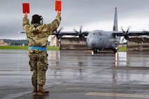 A maintainer assigned to the 374th Aircraft Maintenance Squadron prepares to marshal a U.S. Air Force C-130J Super Hercules at Yokota Air Base Japan, August 16, 2024.