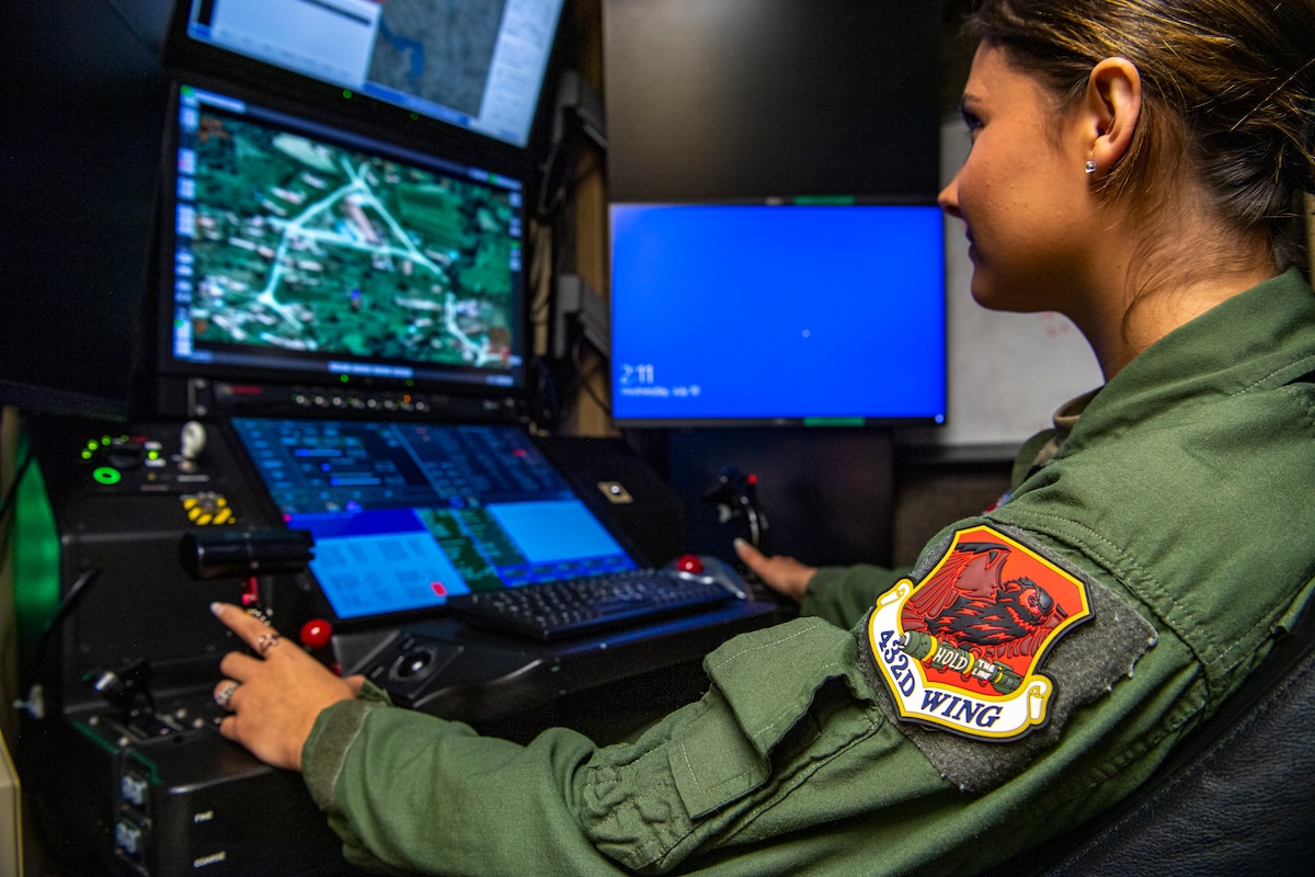 A woman in a flight suit operates a flight simuator.