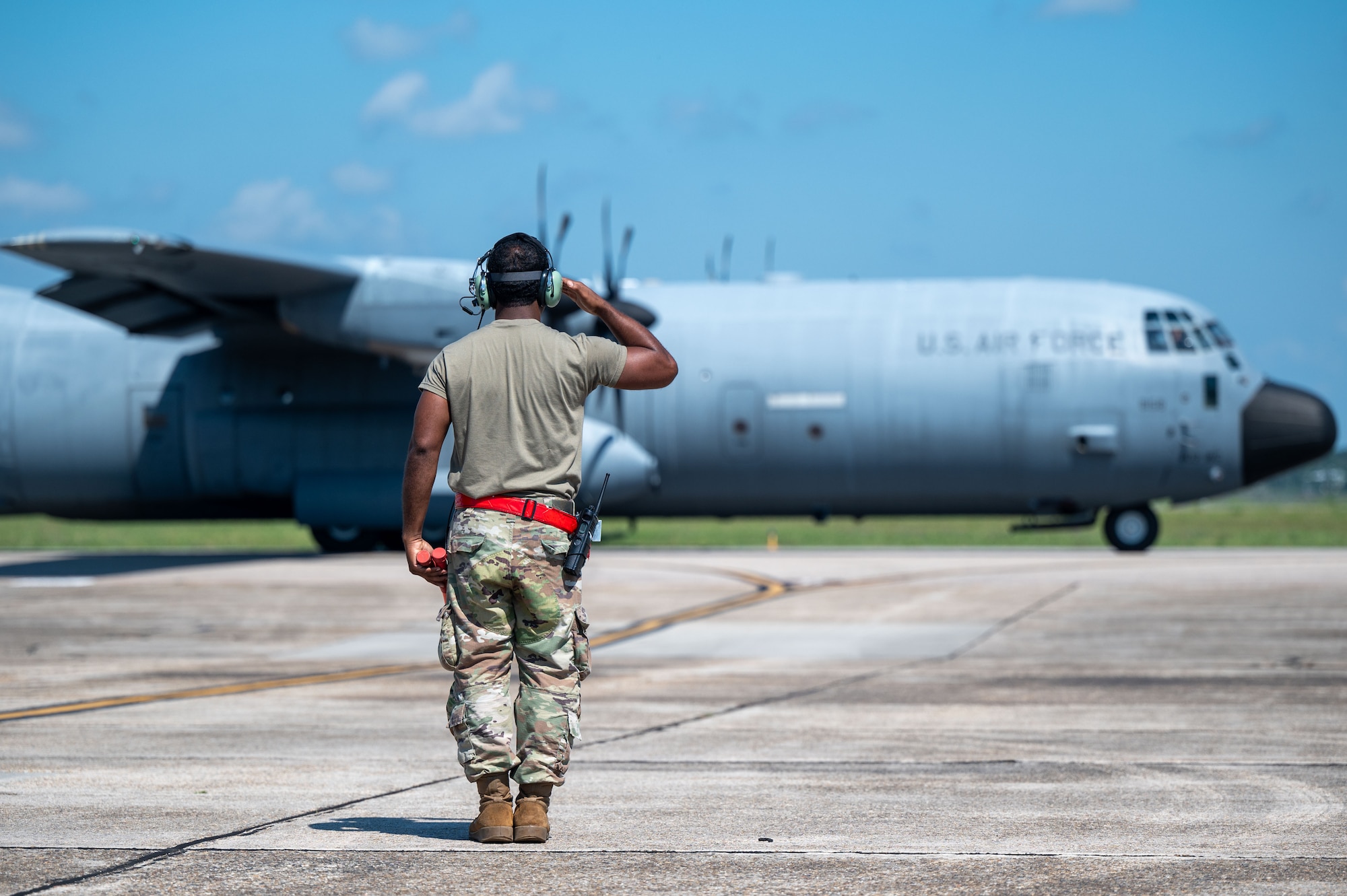 An Airman renders a salute to a C-130J aircraft as it taxis to the runway for takeoff