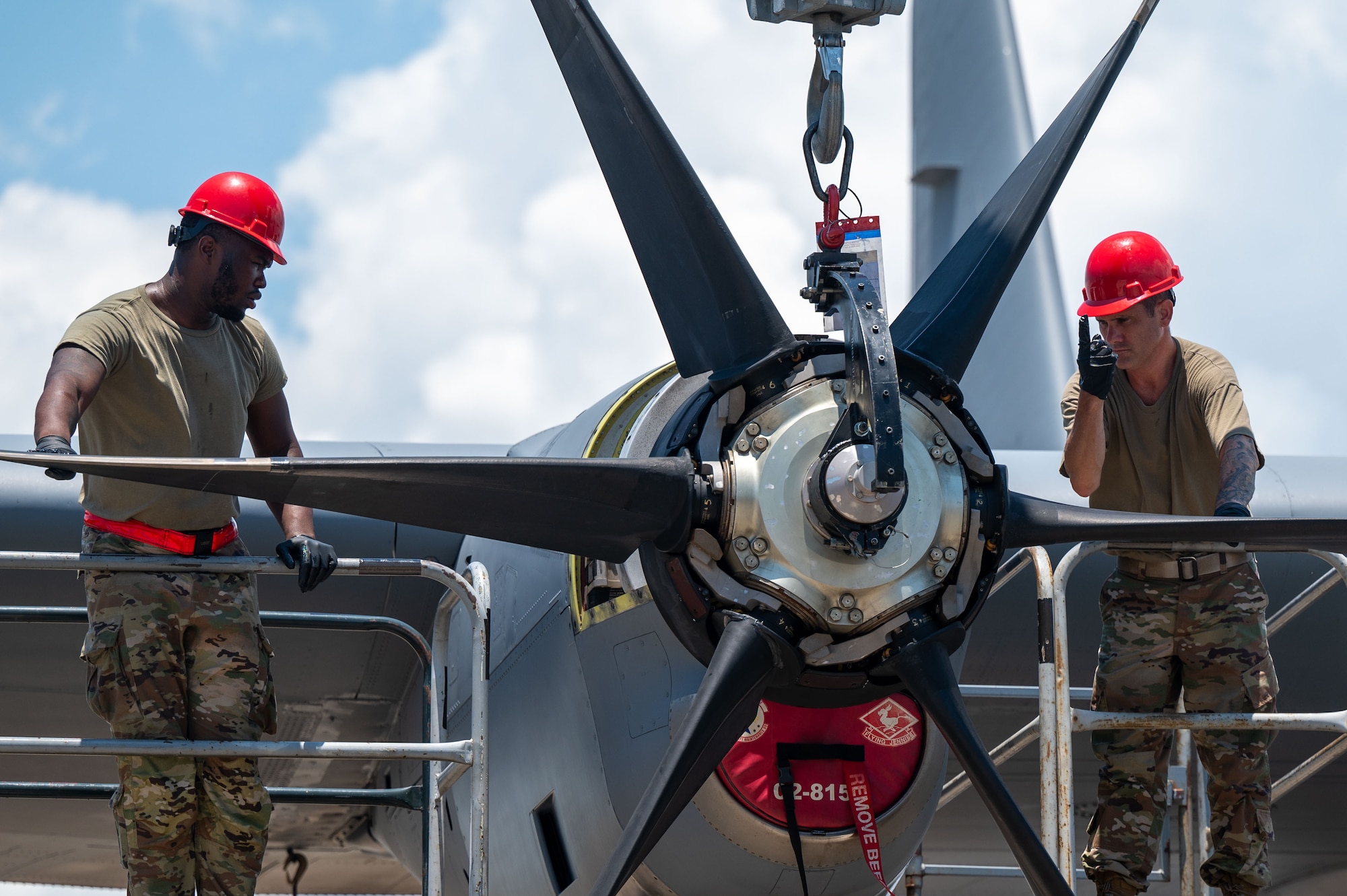 Two Airmen work to install a propeller onto the engine of a C-130J aircraft