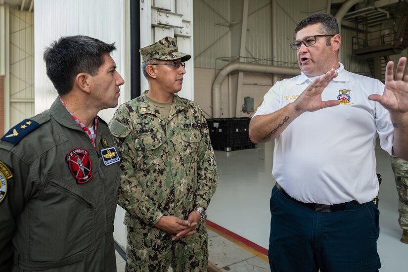 Dustin Behr, right, assistant fire chief at the 123rd Airlift Wing, discusses fire response capabilities with Ecuadorian military officials during a tour of the Kentucky Air National Guard Base in Louisville, Ky., Aug. 6, 2024. The Ecuadorians were visiting as part of the State Partnership Program to learn more about the Kentucky Guard’s emergency response capabilities and interagency cooperation across the state. (U.S. Air National Guard photo by Dale Greer)