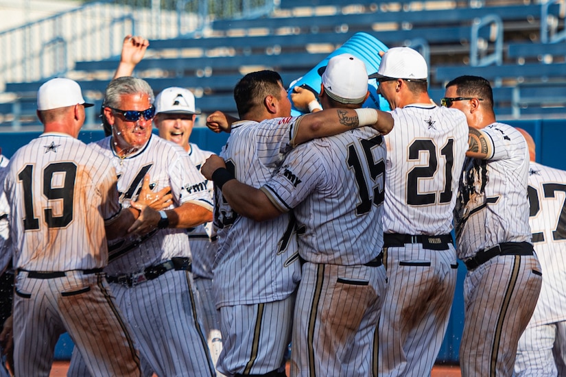 A group of softball players hug each other during a celebration.