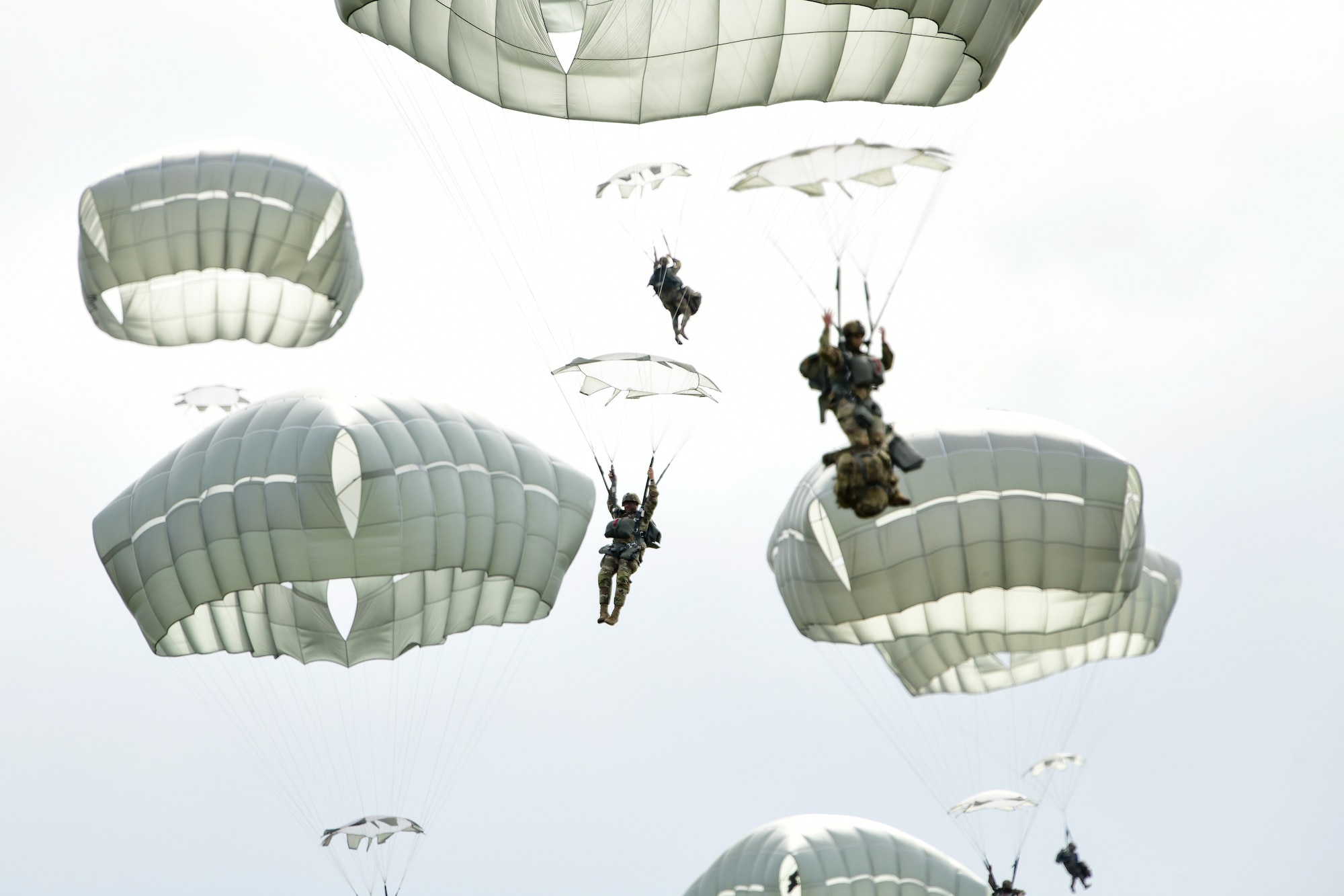 Paratroopers of the 2nd Infantry Brigade Combat Team (Airborne), 11th Airborne Division, the “Arctic Angels”, descend on Malemute Drop Zone at Joint Base Elmendorf-Richardson, Alaska, in a mass parachute exhibition for service members, gathered families, and distinguished guests in celebration of National Airborne Day.
