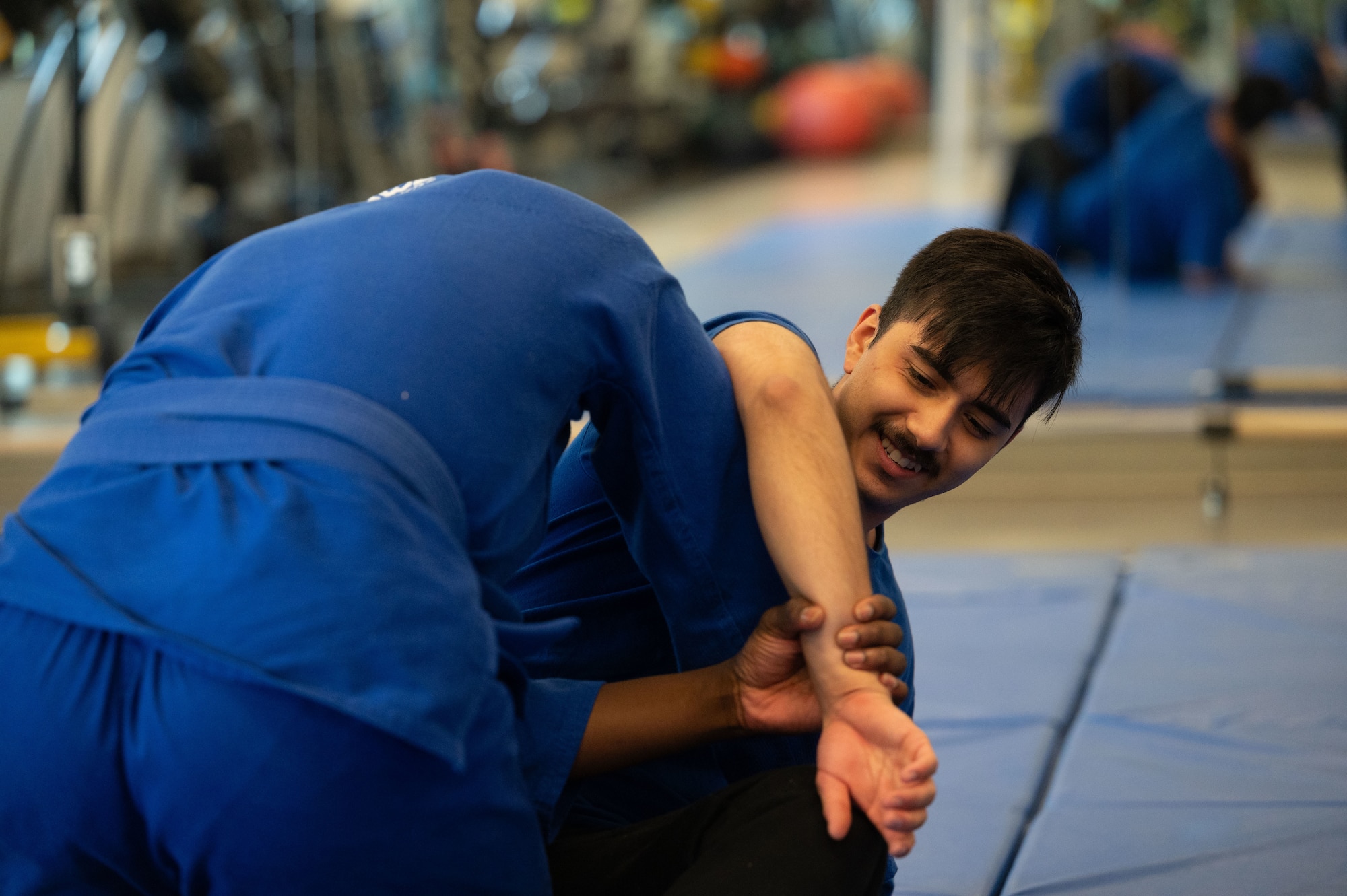 Airman 1st Class Mascorro Esai, right, 436th Maintenance Squadron repair and reclamation journeyman, learns a triangle choke from Senior Airman Class Ojo Olugbenga, left, 436th Comptroller Squadron budget analyst, during a Jujitsu class at Dover Air Force Base, Delaware, Aug. 15, 2024. Dover AFB's fitness center classes have played a role in Airmen maintaining mission-ready fitness. (U.S. Air Force photo by Senior Airman Dieondiere Jefferies)